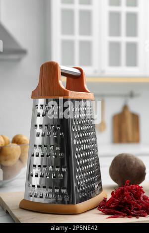 Grater and fresh ripe beetroot on table in kitchen Stock Photo