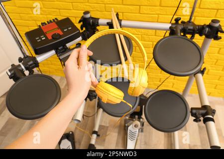 Woman with headphones near modern electronic drum kit indoors, closeup. Musical instrument Stock Photo