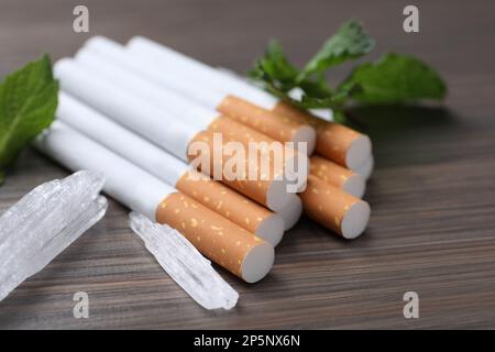 Cigarettes, menthol crystals and mint on wooden table, closeup Stock Photo