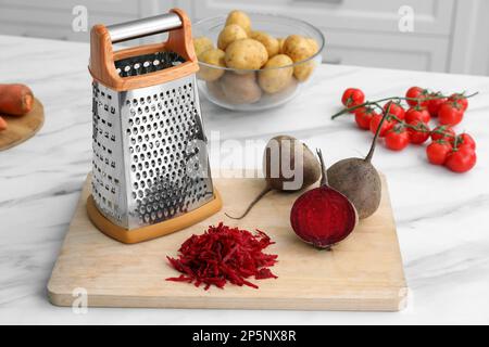 Grater and fresh ripe beetroots on white marble table Stock Photo