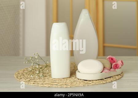 Bottles of shower gel and soap bars on wooden table in bathroom Stock Photo