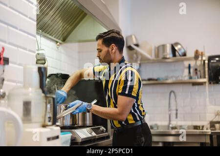 Young man preparing fresh food in commercial kitchen Stock Photo