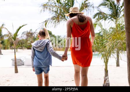 Happy biracial mother and daughter holding hands at beach Stock Photo