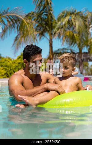 Happy biracial father and son playing together in swimming pool Stock Photo