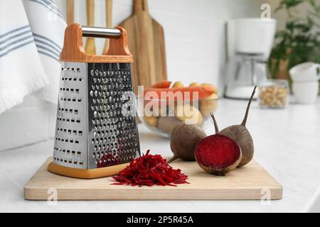Grater and fresh ripe beetroots on kitchen counter Stock Photo