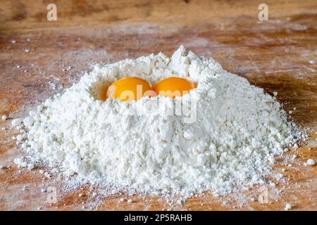 Flour and two egg yolks on wooden board Stock Photo