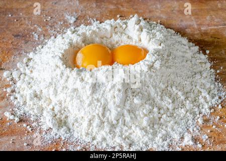 Flour and two egg yolks on wooden board Stock Photo