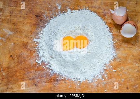 Flour and two egg yolks on wooden board Stock Photo