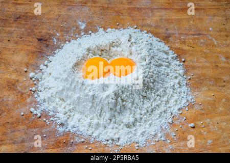 Flour and two egg yolks on wooden board Stock Photo