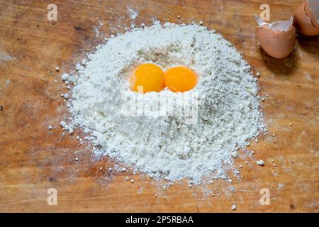 Flour and two egg yolks on wooden board Stock Photo