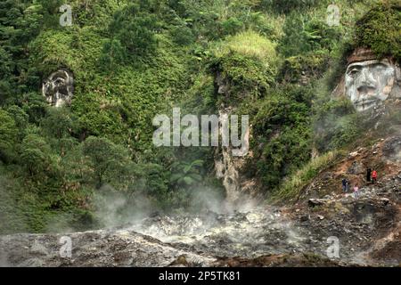 Fumarole fields below the side of a hill where the giant faces illustrating Toar and Lumimuut—the ancestral figures of Minahasan people—are sculptured on Bukit Kasih (Hill of Love), a popular religious tourism destination located in Kanonang village, West Kawangkoan, Minahasa, North Sulawesi, Indonesia. On top of the hillside is a flat ground where worship places of all recognized religions in Indonesia are built. Dedicated to all religious believers and devotees while promoting the spirits of love, peace, and tolerance; Bukit Kasih was initiated in early 2000's. Stock Photo