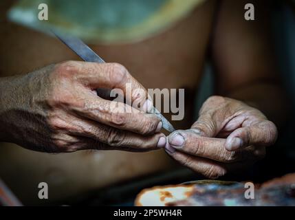 A close up of the hands of a jeweller and goldsmith inside the Central Market in Phnom Penh, Cambodia. Stock Photo