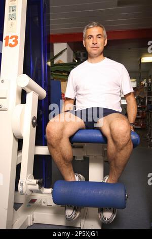 elderly man working out on the leg curl at the gym Stock Photo