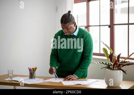 African American Guy Making Technical Drawing Using Compass In Office Stock Photo