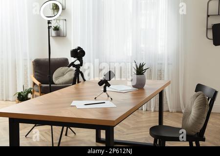Camera and lighting equipment on tripods near table in room. Blogger workplace Stock Photo