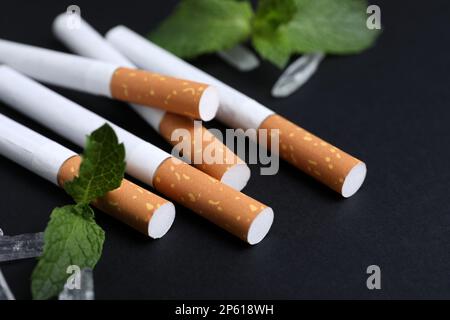 Cigarettes, menthol crystals and mint on black background, closeup Stock Photo