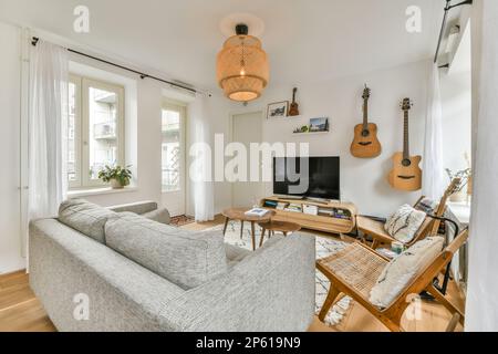 a living room with a guitar hanging on the wall and a couch in the fore - eyed corner next to it Stock Photo