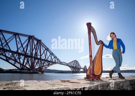 Composer, harpist and singer Esther Swift alongside her Italian Salvi pedal harp during a photocall ahead of her upcoming tour, at the Forth Bridge in North Queensferry. Ms Swift will tour across Scotland solo this month with a programme of original compositions and traditional works. Picture date: Tuesday March 7, 2023. Stock Photo