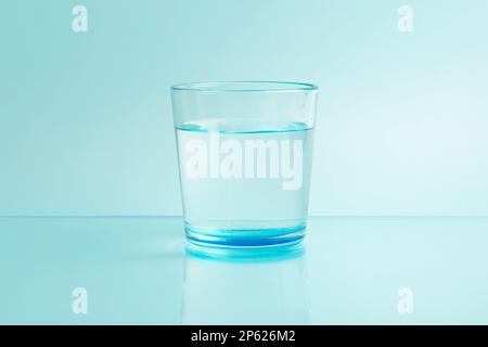 Glass with pure clear melt water on a blue background Stock Photo
