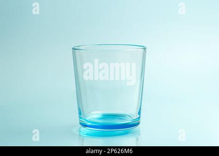 Clear drinking glass isolated on cyan blue background Stock Photo