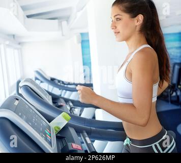 She takes care of her body. A beautiful young woman exercising on a treadmill at the gym. Stock Photo