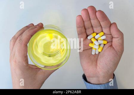 top view of man hand holding pills and glass of water on a white background top view Stock Photo