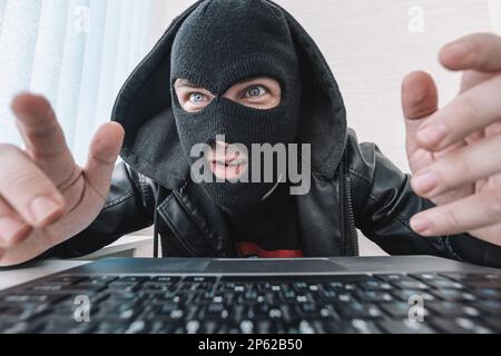 Thieves hold credit cards using a laptop computer for password hacking activities. Cyber crime concepts. a male thief holds a credit card in his hand Stock Photo