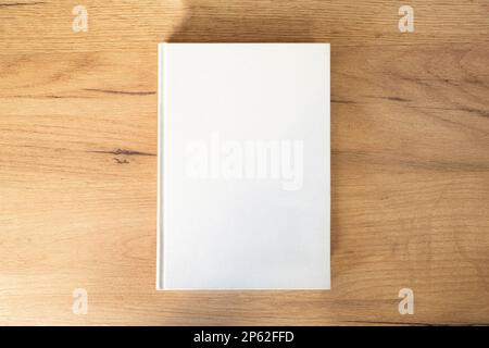 a white book with an empty pesto for text and design on a wooden background Stock Photo
