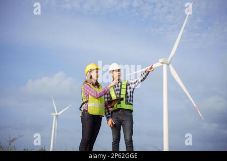 Team of asian engineers discussing and progress check wind turbine field. Stock Photo