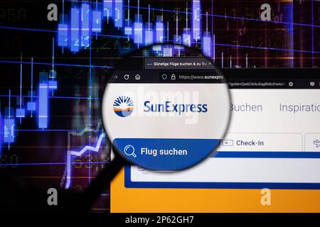 Sun Express, airline company logo on a website with blurry stock market developments in the background, seen on a screen through a magnifying glass Stock Photo