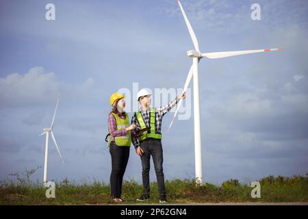 Team of asian engineers discussing and progress check wind turbine field. Stock Photo