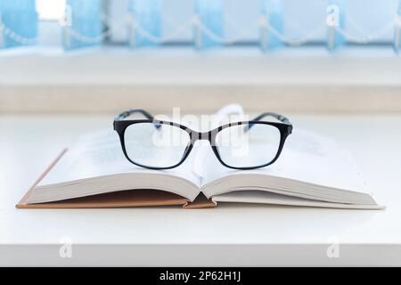 A pair of designer glasses on an opened book. Stock Photo