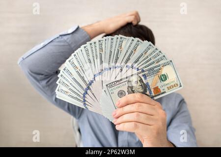Young businessman holding dollar money on white background, businessman think idea about finance for success, male holding cash with banknote and ques Stock Photo
