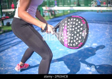 Young sportswoman and man couple playing padel tennis in slow motion. Hitting padel ball in slow mo at padel court. Stock Photo