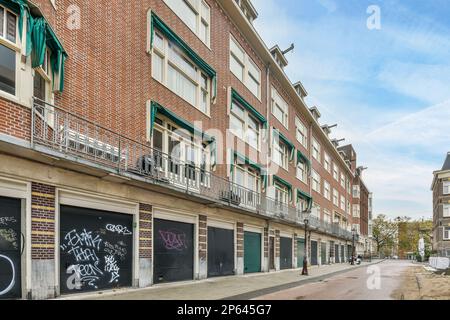 Amsterdam, Netherlands - 10 April, 2021: a brick building with graffiti written on the side and balk's sign in the middle, along an empty street Stock Photo