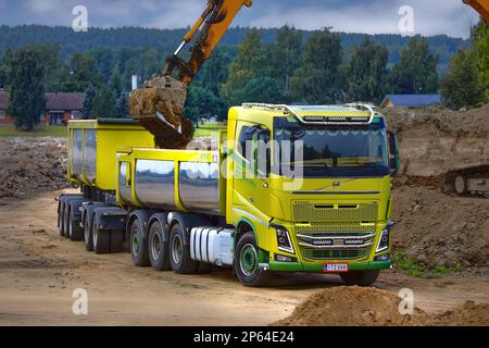 Tracked excavator loading soil onto green Volvo FH16 truck cassette trailer. Salo, Finland. August 27, 2022. Stock Photo