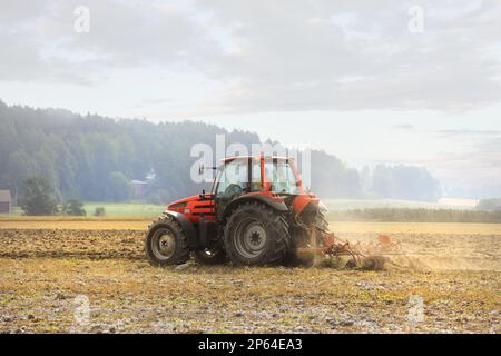 Plowing the field with Same farm tractor and plough on a misty day of early autumn, side view. Salo, Finland. August 27, 2022. Stock Photo