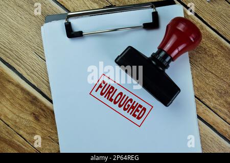 Concept of Red Handle Rubber Stamper and Furloughed text isolated on on Wooden Table. Stock Photo