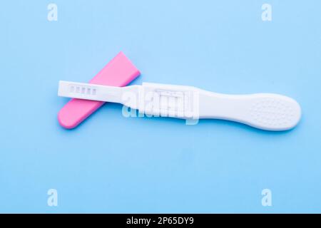 Unused pink and white pregnancy test on the blue background. Stock Photo