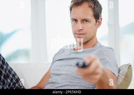 Hes serious about his weekend sport. a handsome man holding a remote control. Stock Photo