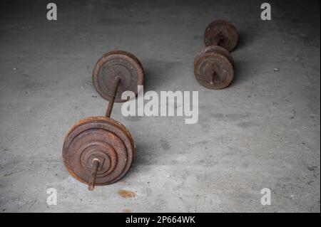 A pair of rusty and vintage dumbbells on a concrete floor Stock Photo