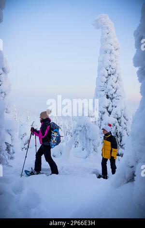 Cheerful mother with son snowshoeing in the frozen forest, Oulanka National Park, Ruka Kuusamo, Lapland, Finland, Europe Stock Photo