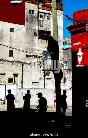 Silhouetted figures against brightly coloured buildings, basketball net on street corner, San Martin, Old Havana, Cuba, West Indies, Caribbean Stock Photo