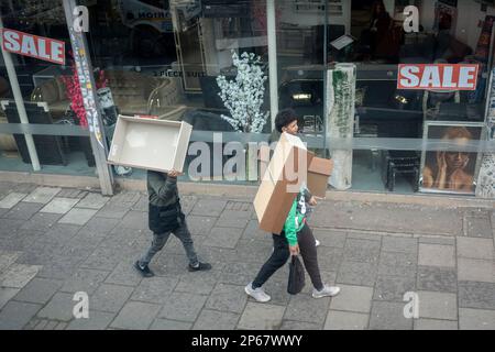 Three men each carry a piece of furniture, drawers for a home somewhere, down the Walworth Road in Camberwell, south London, on 7th March 2023, in London, England. Stock Photo