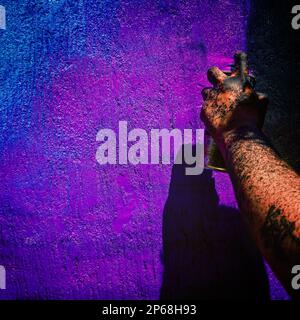 A hand of a Mexican street artist, splashed with black paint, is seen painting graffiti on the wall of a cemetery during a graffiti event in Guadalajara, Mexico. Stock Photo