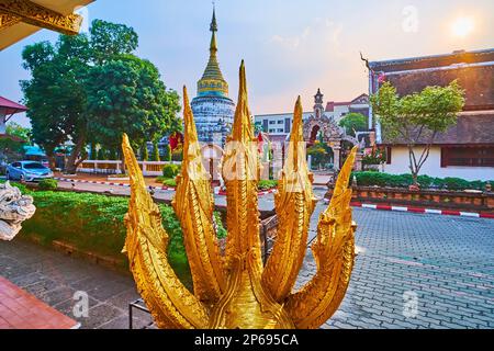 The five-headed golden Naga serpent against the medieval chedi and bright sunset sky, Statues in Wat Buppharam, Chiang Mai, Thailand Stock Photo
