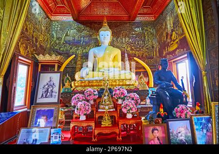 CHIANG MAI, THAILAND - MAY 3, 2019: The white teak Buddha altar in shrine-library of Wat Buppharam with gilt reliefs on walls in background, Chiang Ma Stock Photo