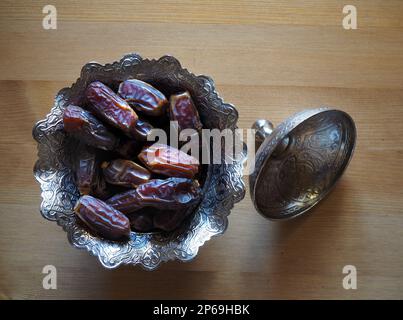 Dried date fruit. Traditional Ramadzan food for Muslims. Ramadan Kareem background or banner. Dried dates on wooden background. Stock Photo