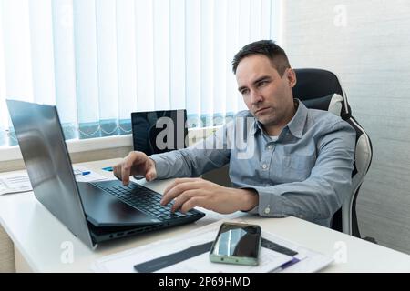 He is using touchpad while reading an e-mail on laptop . Multi-tasking businessman working in the office. Stock Photo