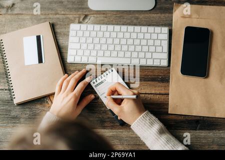 Top view on a woman writes in a notebook plans for the working week at the workplace. Stock Photo